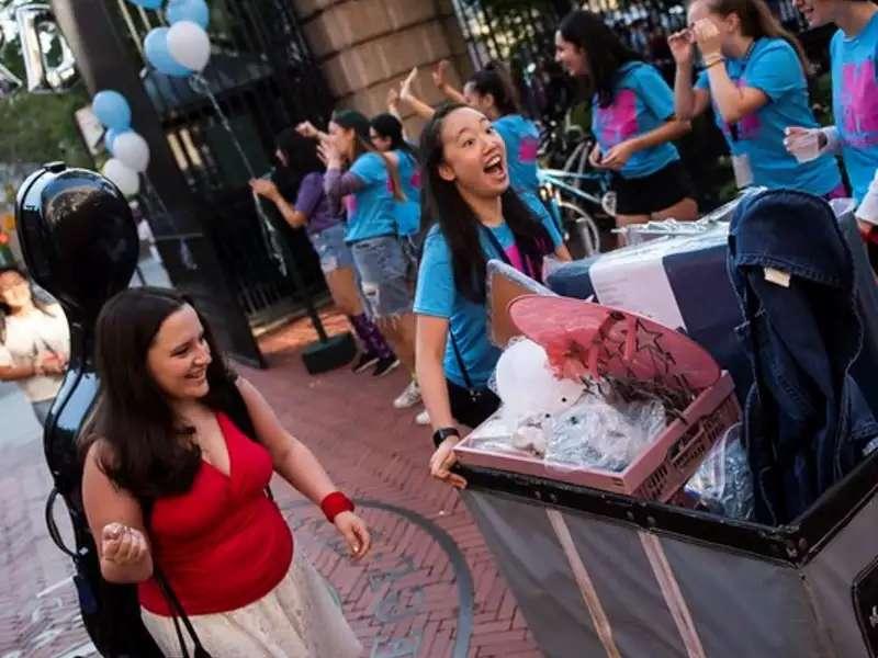 Happy student pushing a cart with her stuff on move-in day